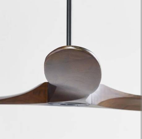 Close-up of a ceiling fan with wooden blades and metallic finish on a white background