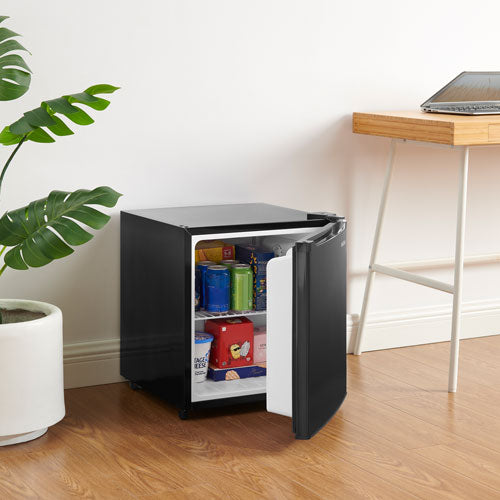 Small black refrigerator with open door revealing snacks in a room with a plant and table.