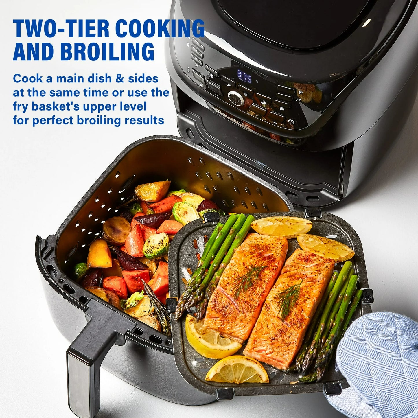 Air fryer with salmon, vegetables, and lemon wedges inside, showing two-tier cooking and broiling capabilities.