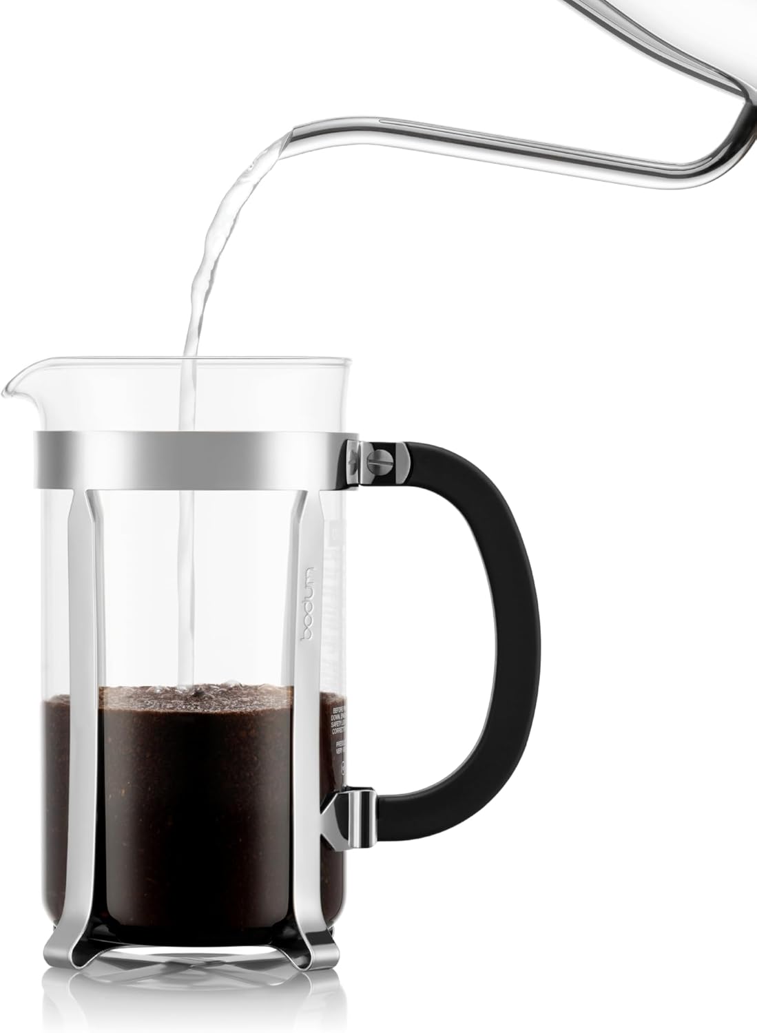 Glass French press with coffee being poured into it on a white background