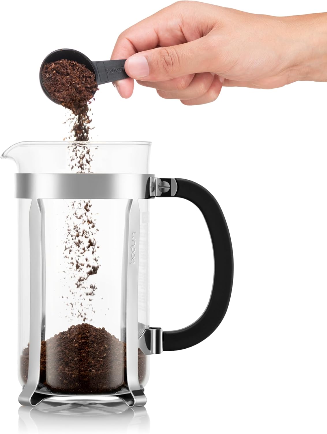 Hand pouring coffee grounds into a French press