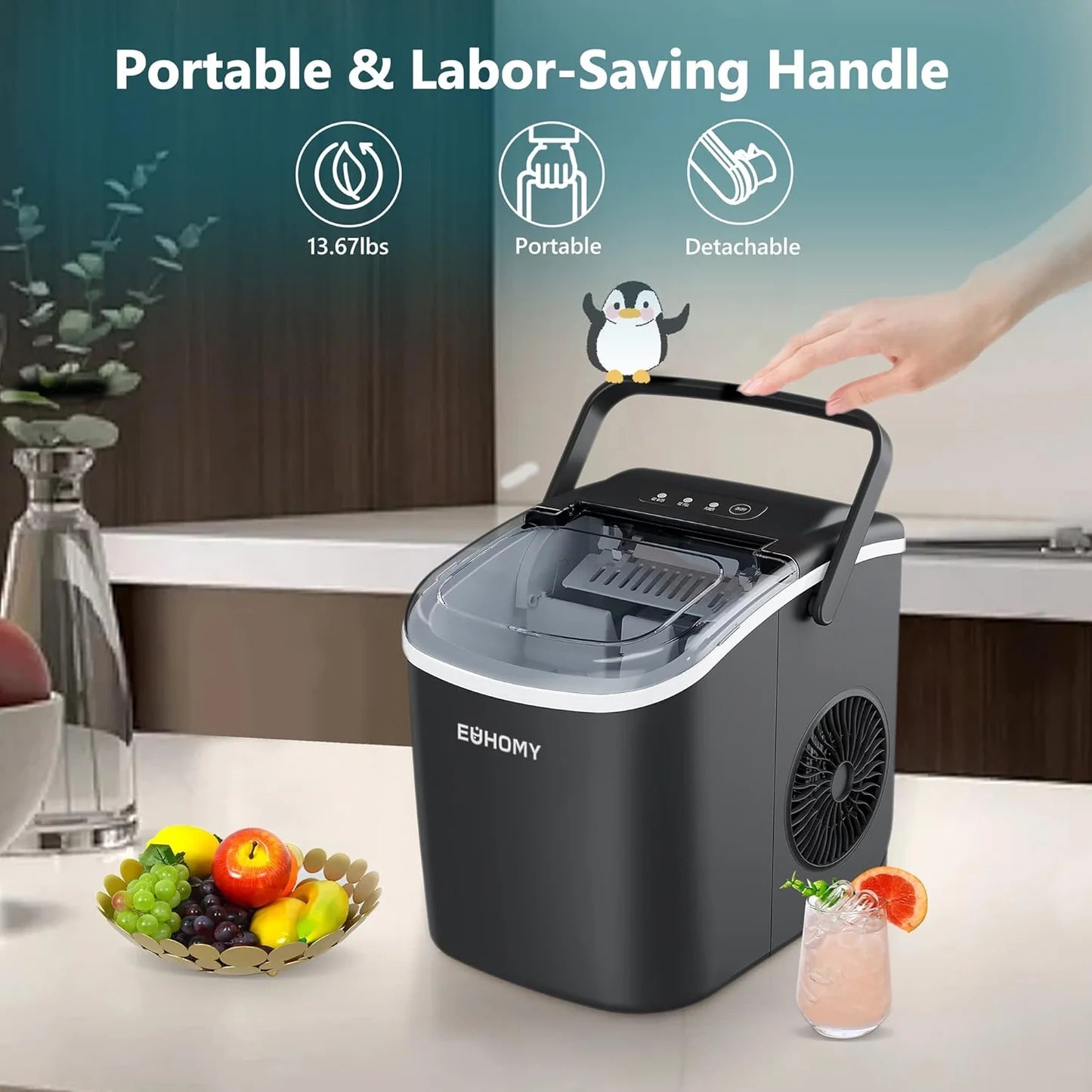 Portable ice maker with a detachable handle on a kitchen counter, surrounded by fruits and a drink.