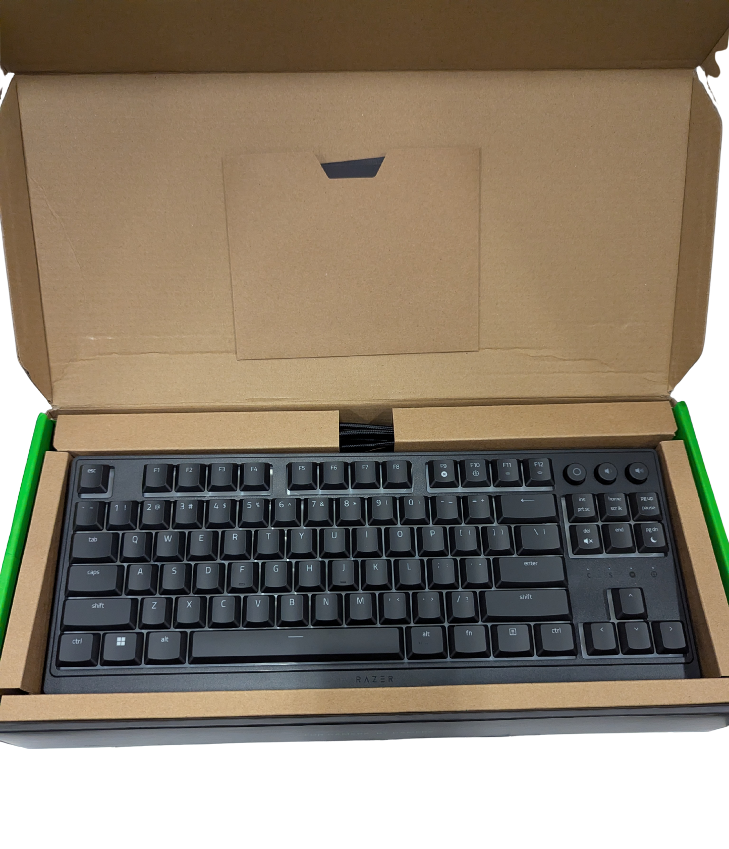 Black keyboard inside an open cardboard box on a white background