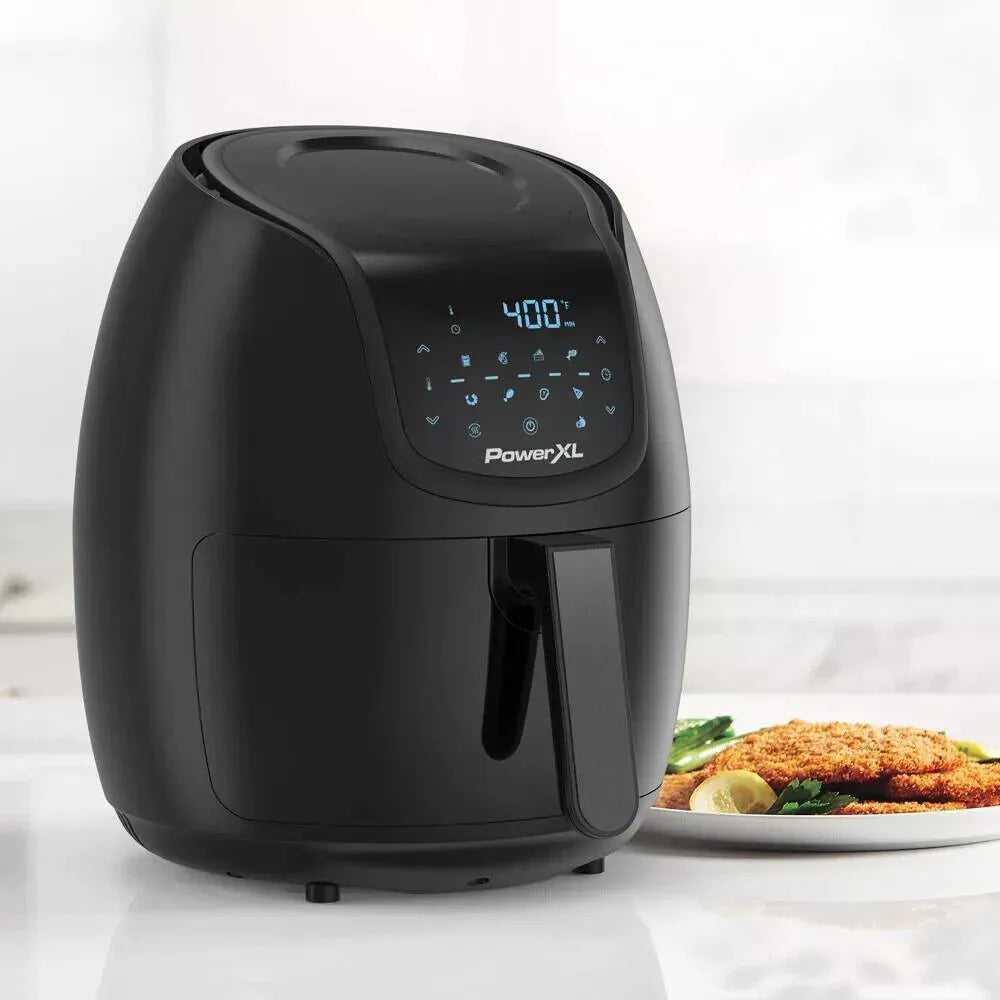 Black PowerXL air fryer on a white surface with a plate of food in the background
