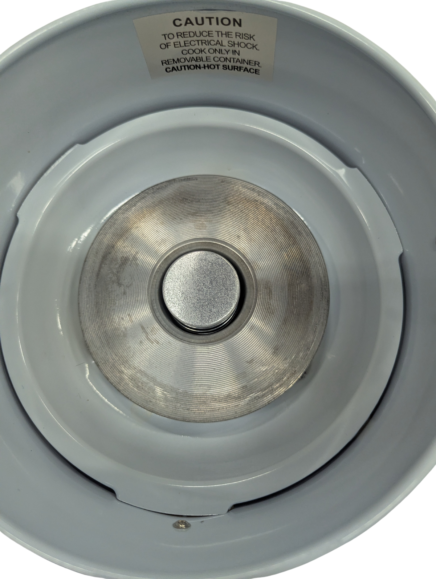 Close-up of a metal stove burner with a warning label on a white background