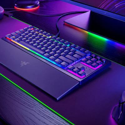 Gaming setup with Razer keyboard, mouse, and headset on a desk with RGB lighting.