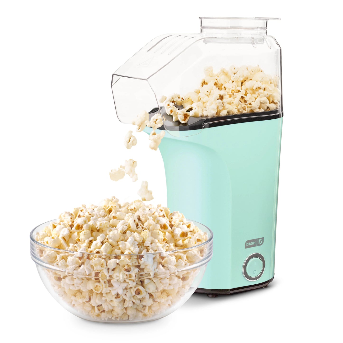 Turquoise popcorn maker with popped popcorn spilling into a clear bowl on a white background