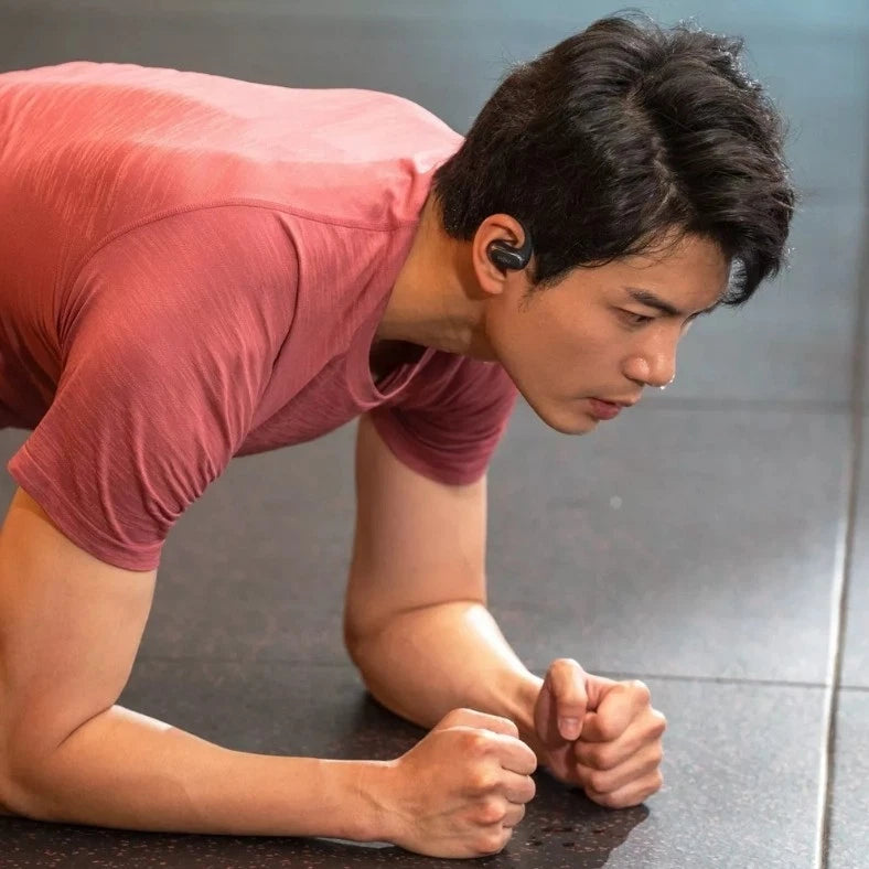 Person in a pink shirt doing push-ups on a gray floor.