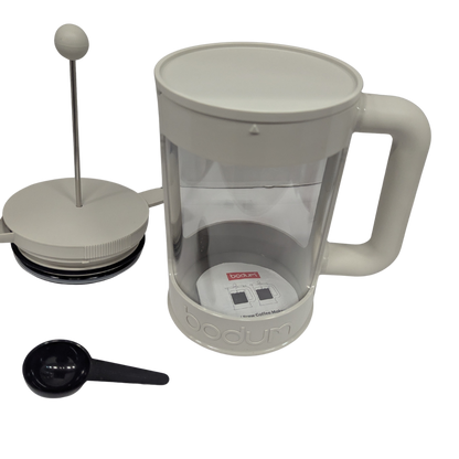 White French press coffee maker with a black scoop on a white background