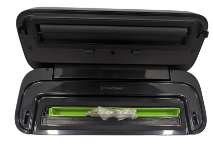 Black FoodSaver vacuum sealer with a green sealing bar on a white background