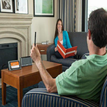 Two people in a living room setting with a tablet and book.