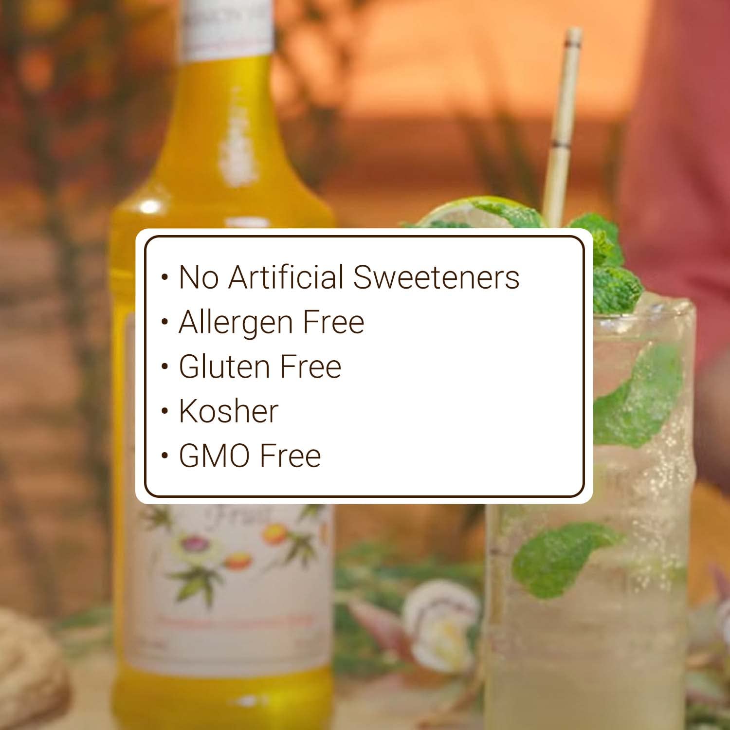 Bottle of a beverage with a glass of a green drink and a straw, set against a blurred background.