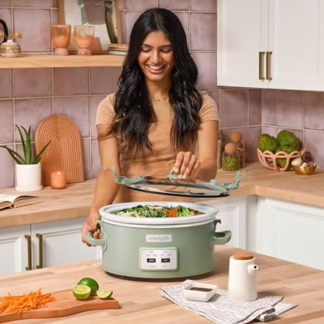 Woman in a kitchen with a Crock-Pot slow cooker, surrounded by kitchen items.