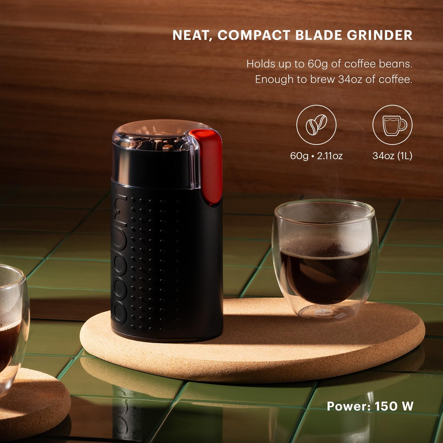 Black blade grinder with red accent on a wooden coaster next to a glass of coffee, with text about capacity and power.