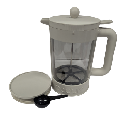 French press coffee maker with a clear glass body and gray plastic lid and handle on a white background.