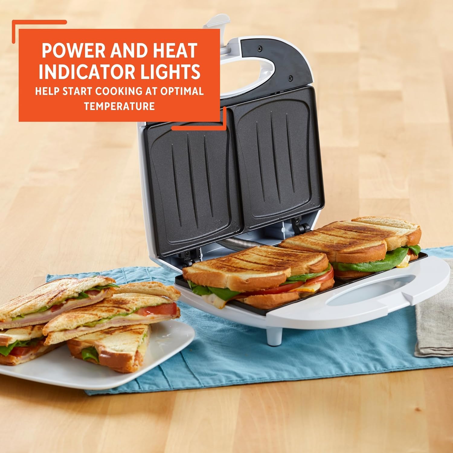 Sandwich maker with toasted sandwiches on a wooden surface, featuring an indicator light feature.