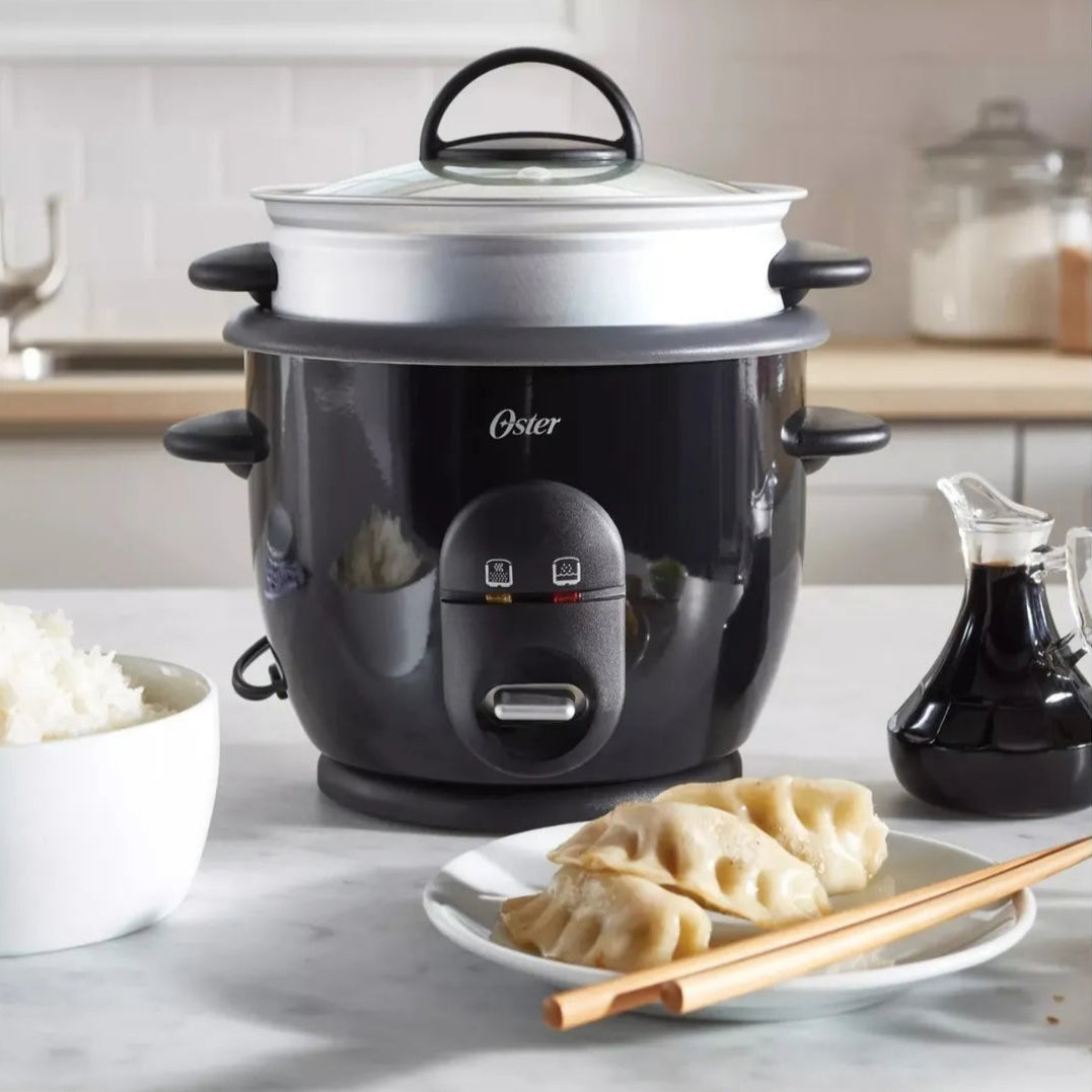 Black rice cooker with a plate of dumplings on a kitchen counter