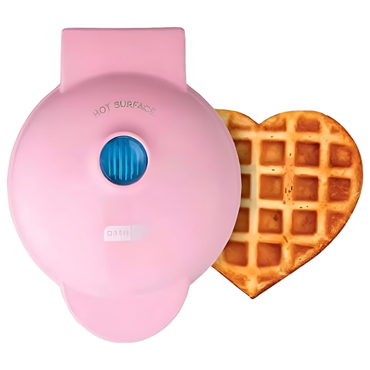 Pink heart-shaped waffle maker next to a heart-shaped waffle on a white background