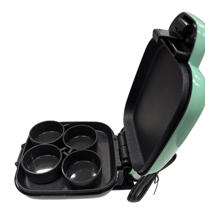 Mint green and black appliance with four round compartments on a white background