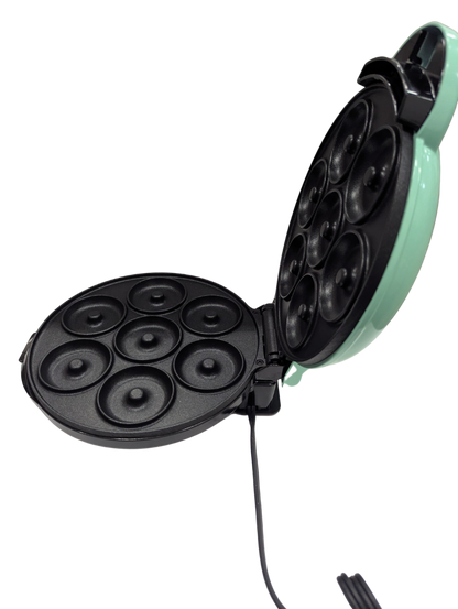 Mint green and black electric mini muffin maker on a white background