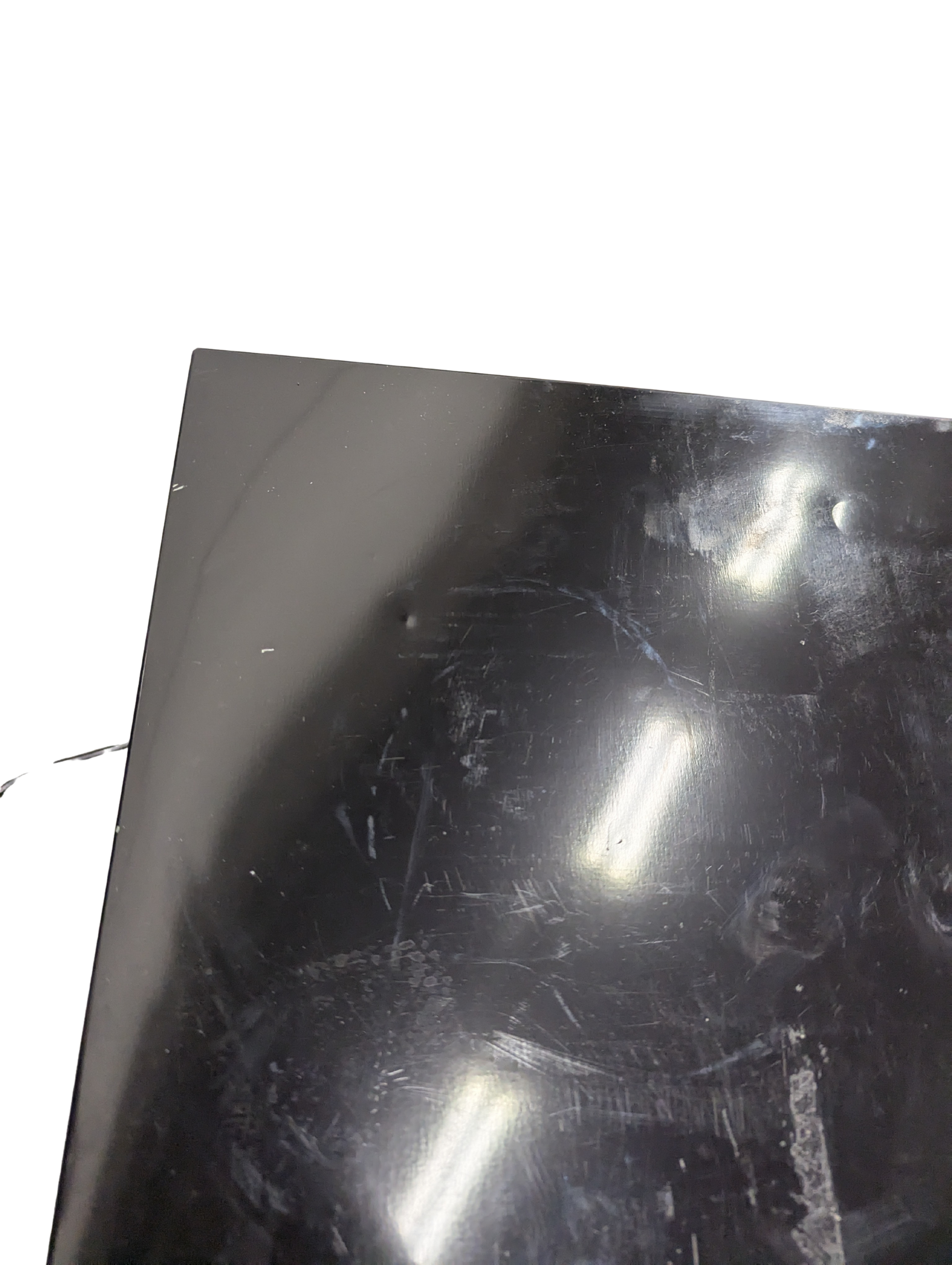 Scratched black surface with reflections on a white background