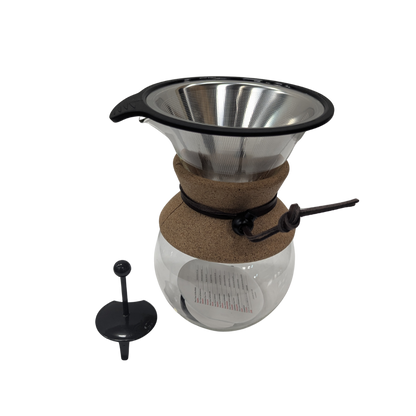 Coffee brewing apparatus with glass carafe and metal filter on a white background