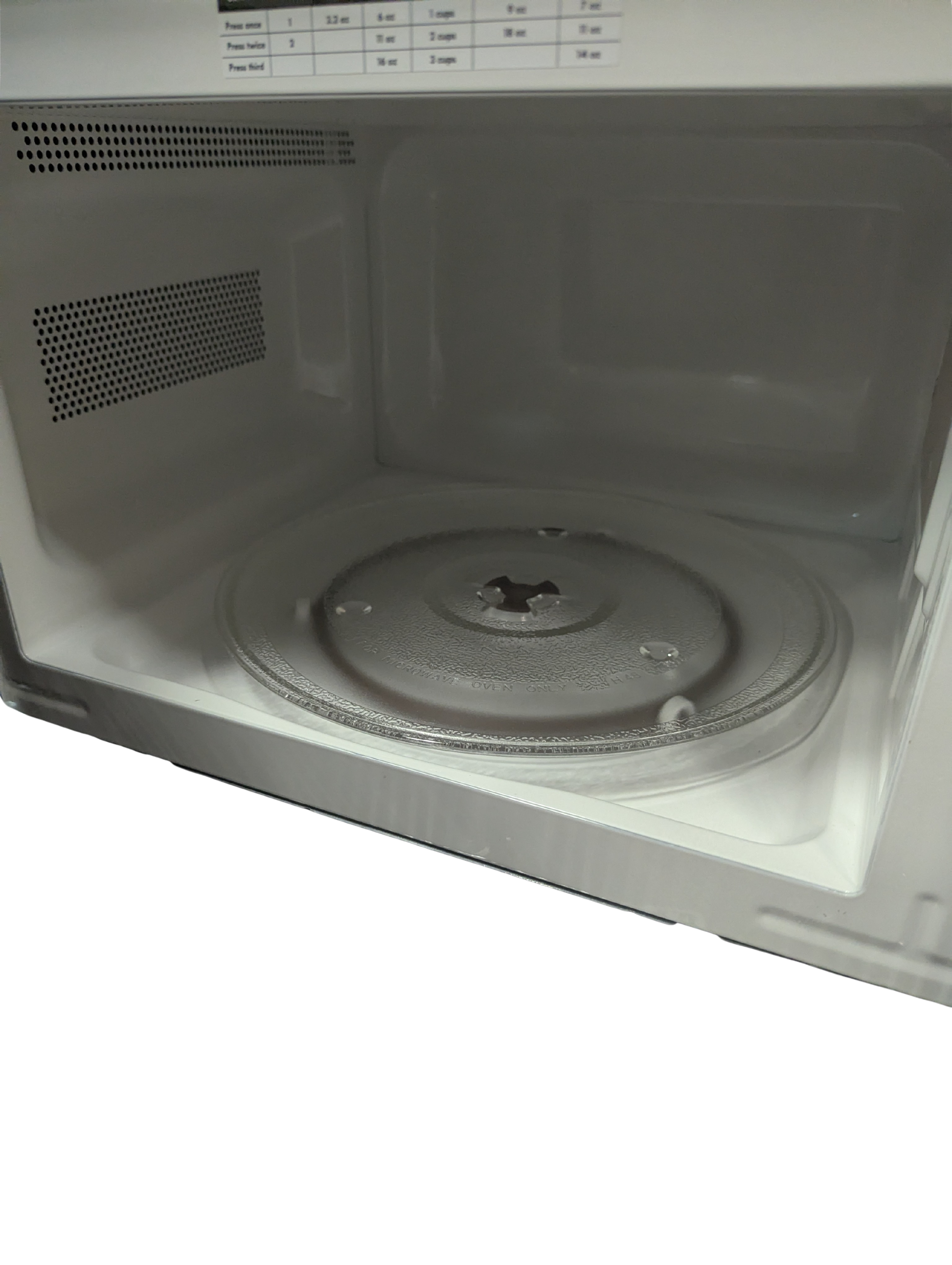 Empty microwave interior with turntable on a white background